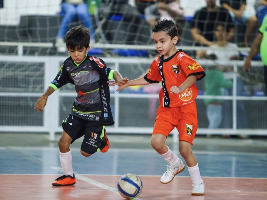 Caio disputando a bola com um adversário em partida de futsal