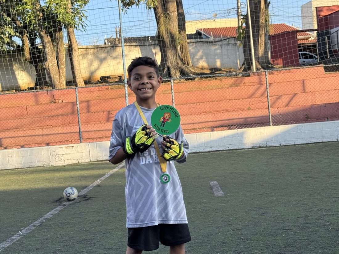 Phelipe com luvas de goleiro e o troféu que conquistou